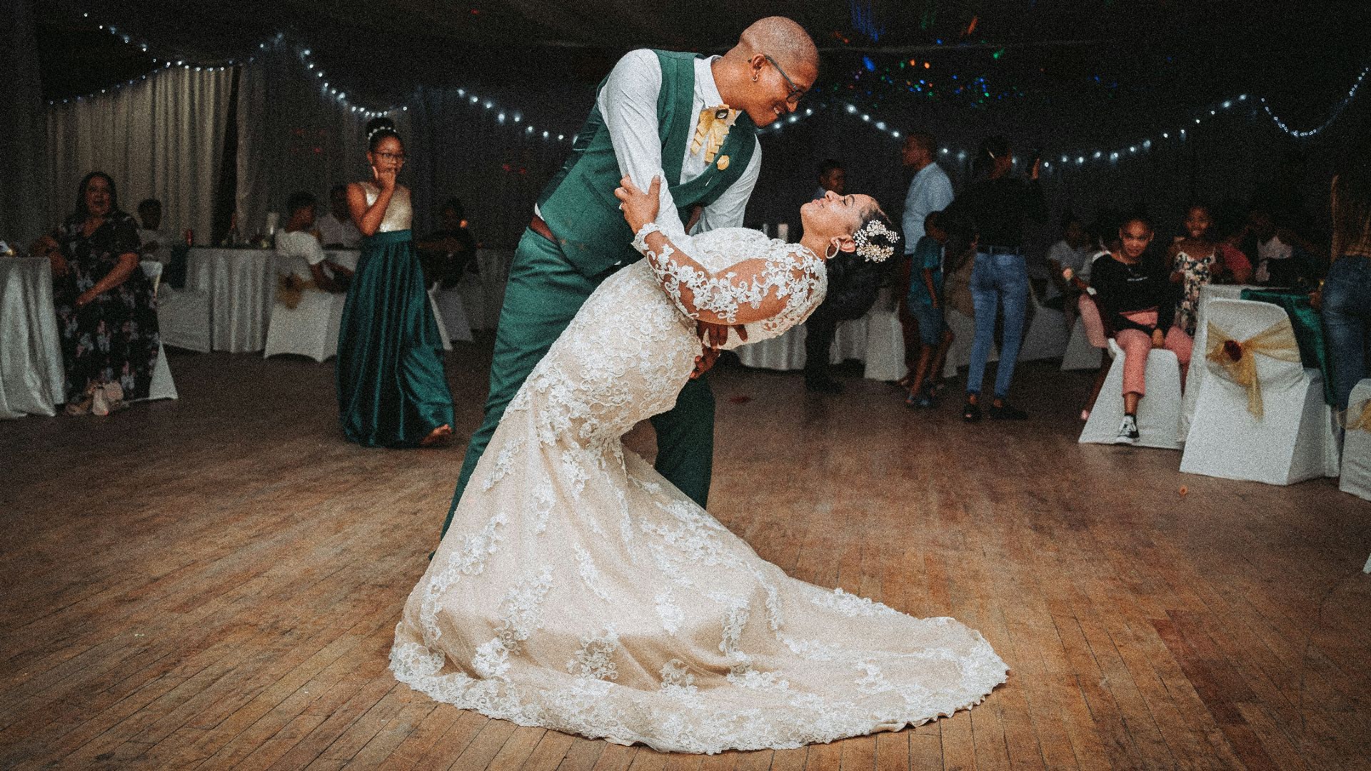 man in black suit jacket holding woman in white wedding dress