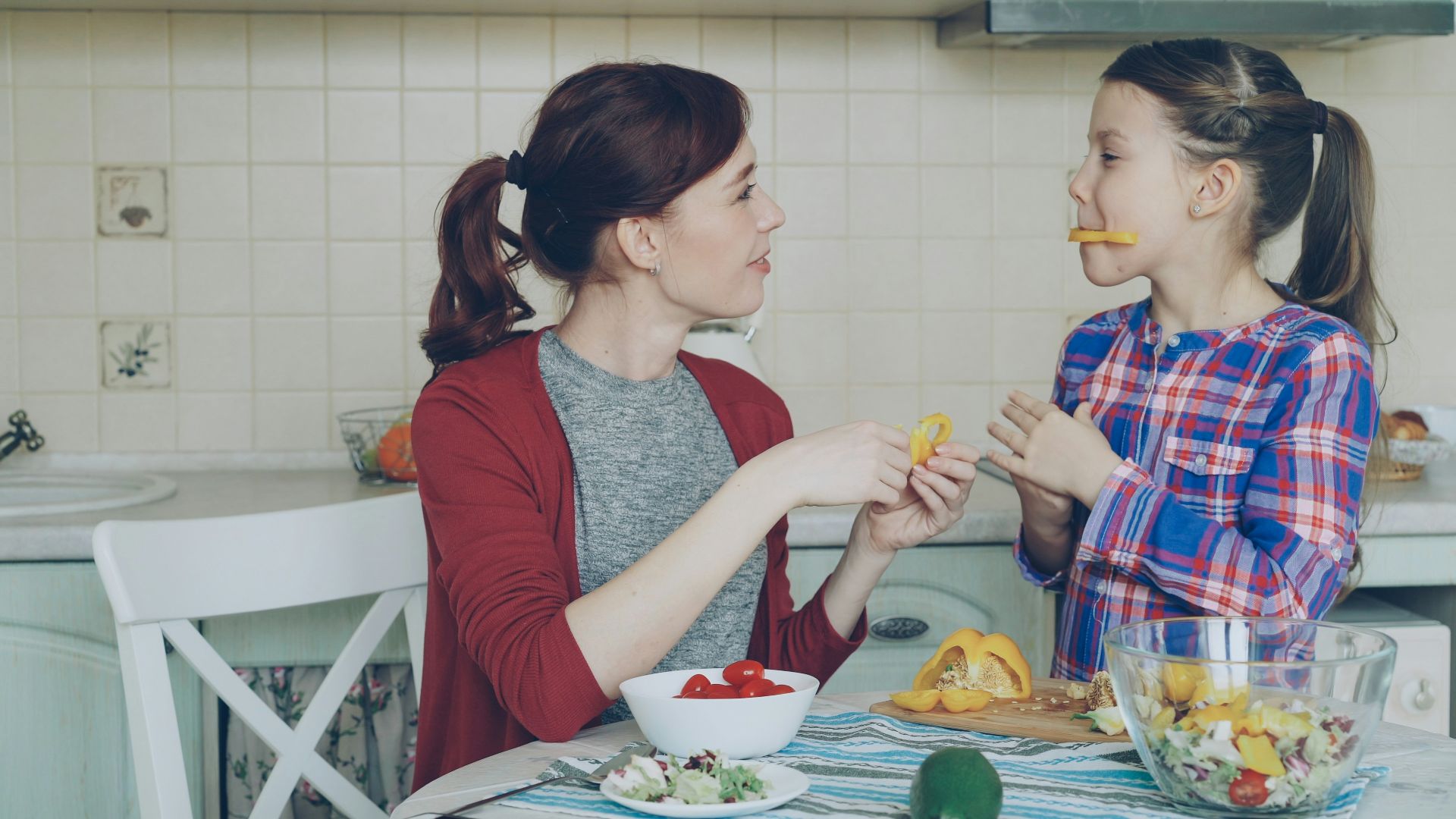 Mother and daughter enjoy snacks in the kitchen.
