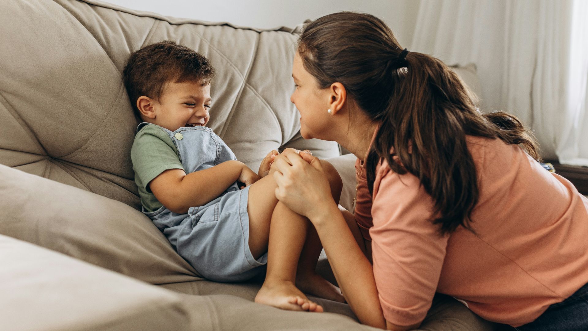 a woman sitting on top of a couch next to a little boy