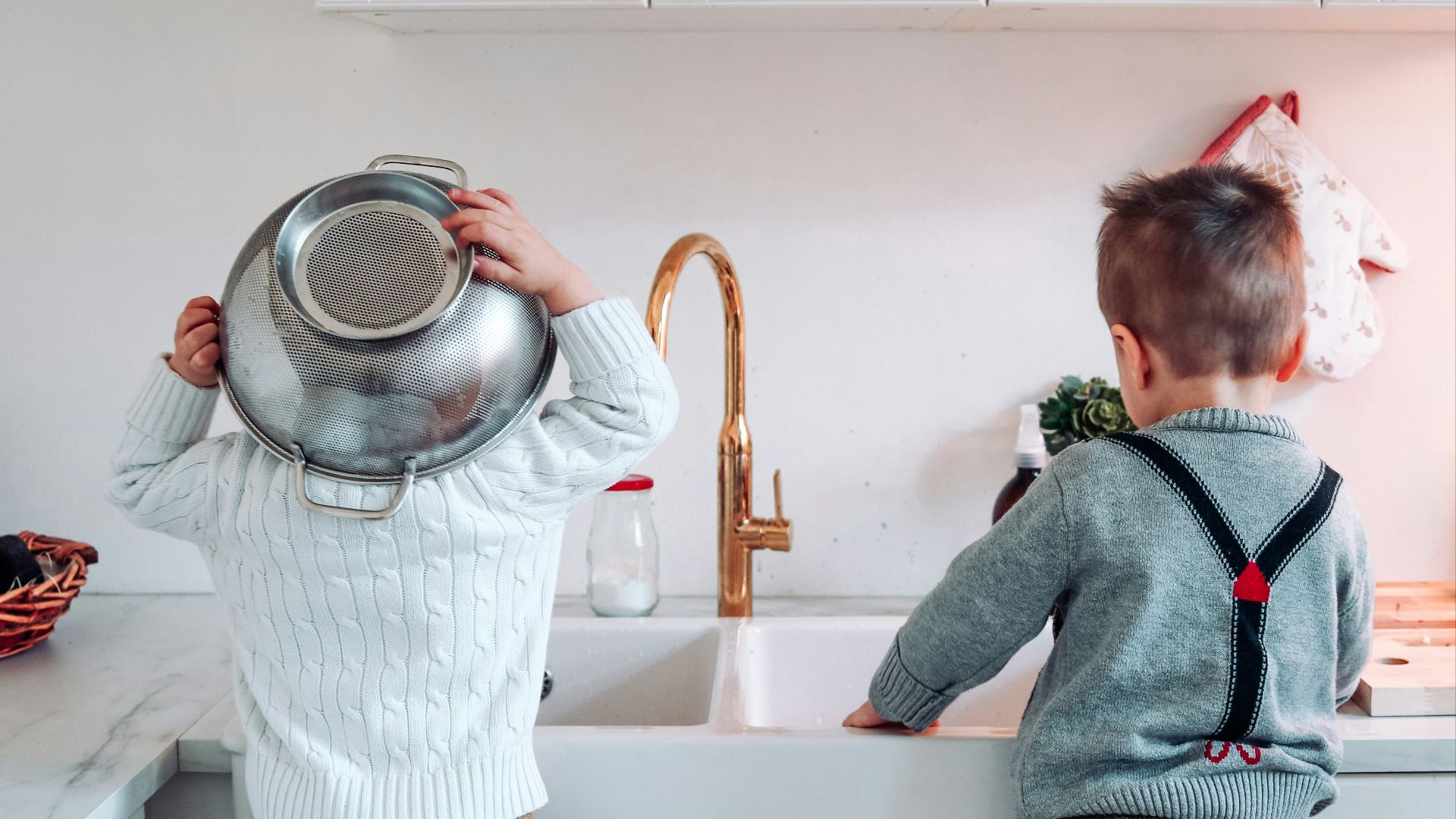 two boys standing on chair near sink