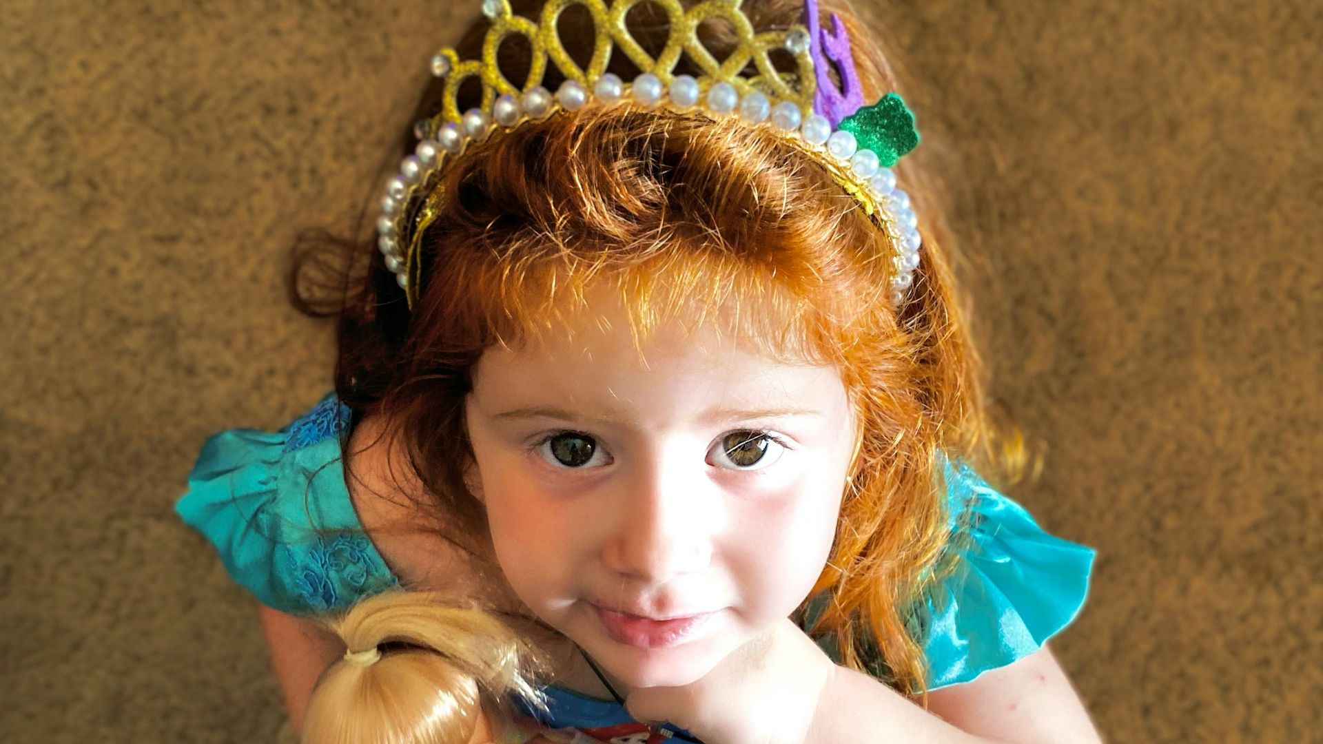 girl in teal sleeveless dress with gold crown