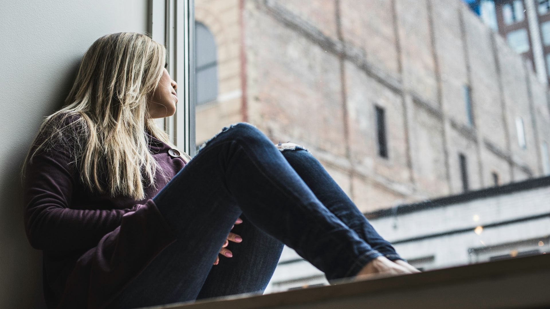 woman sitting on window watching sky