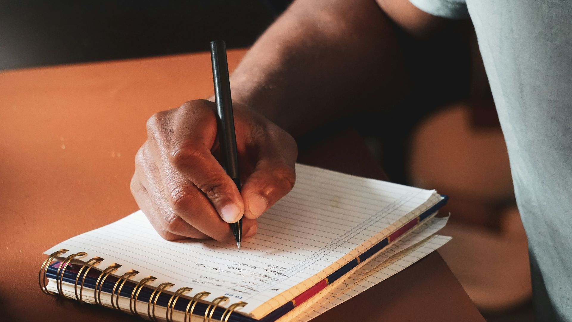 a person writing on a notebook with a pen