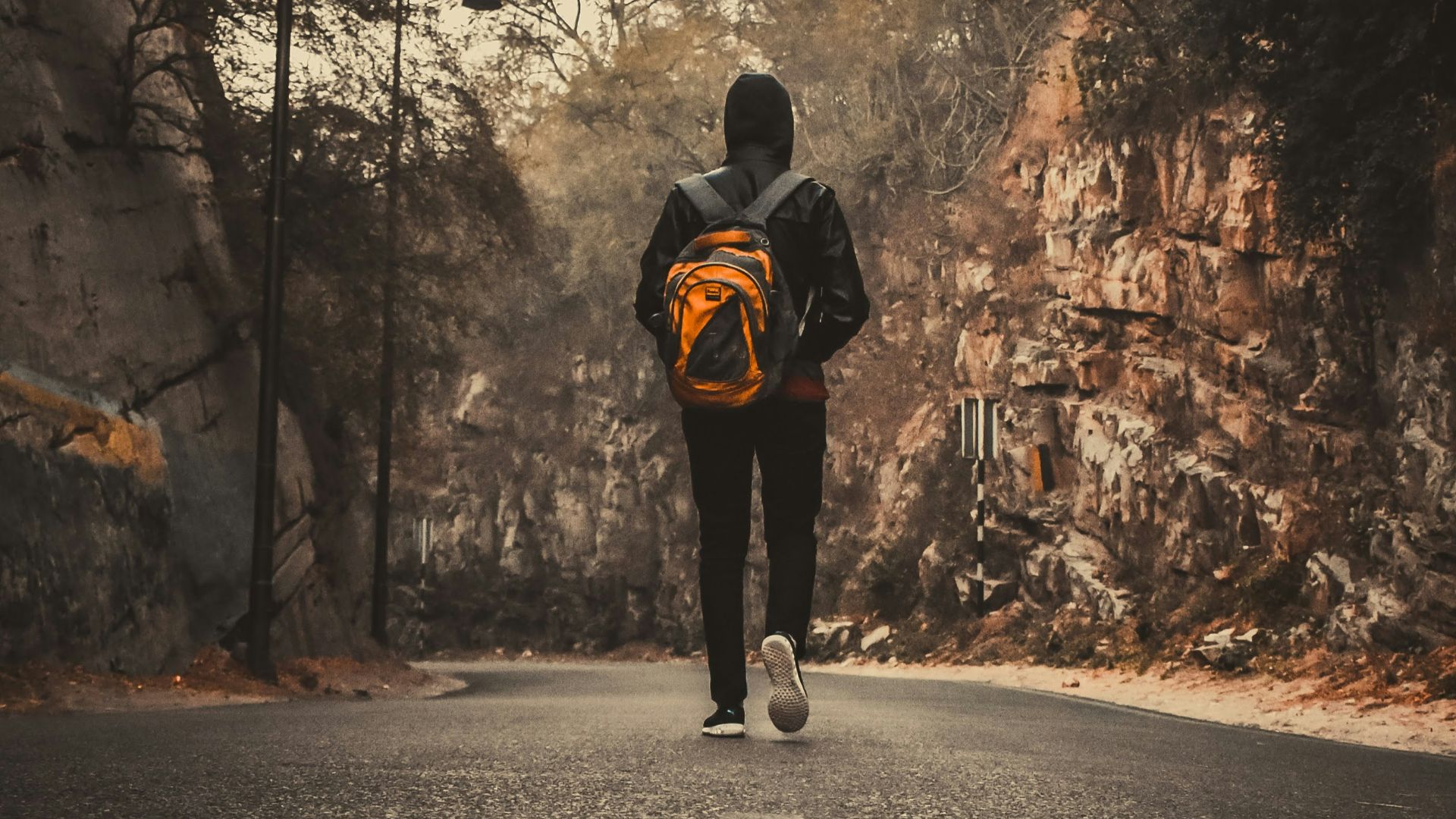 man in black jacket and black pants walking on road during daytime