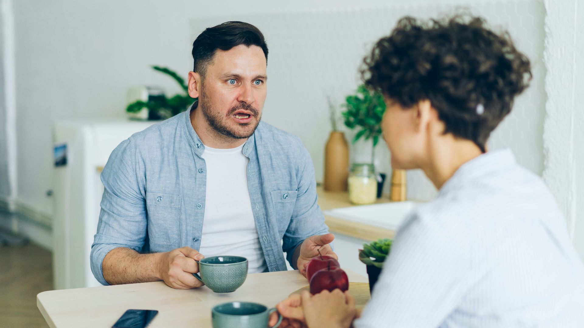 a man sitting at a table talking to a woman