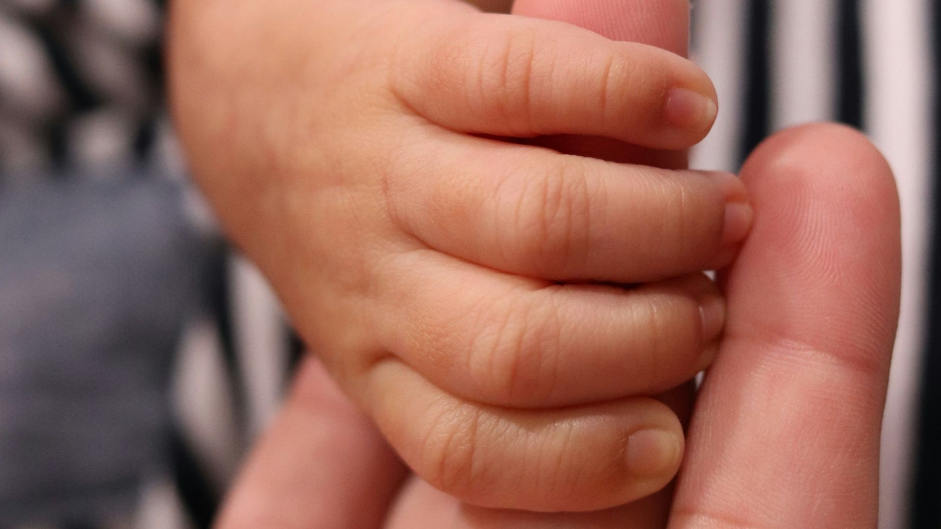 a person holding a baby's hand in their left hand