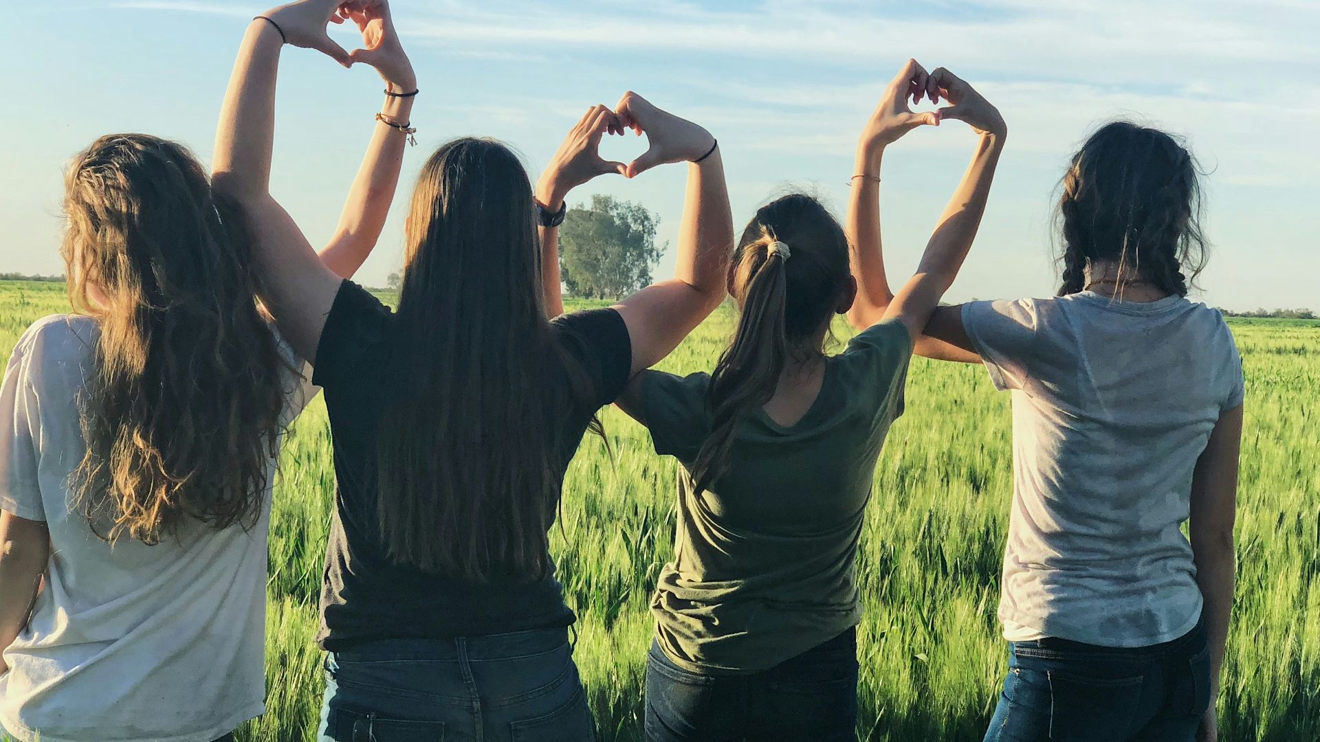 women forming heart gestures during daytime