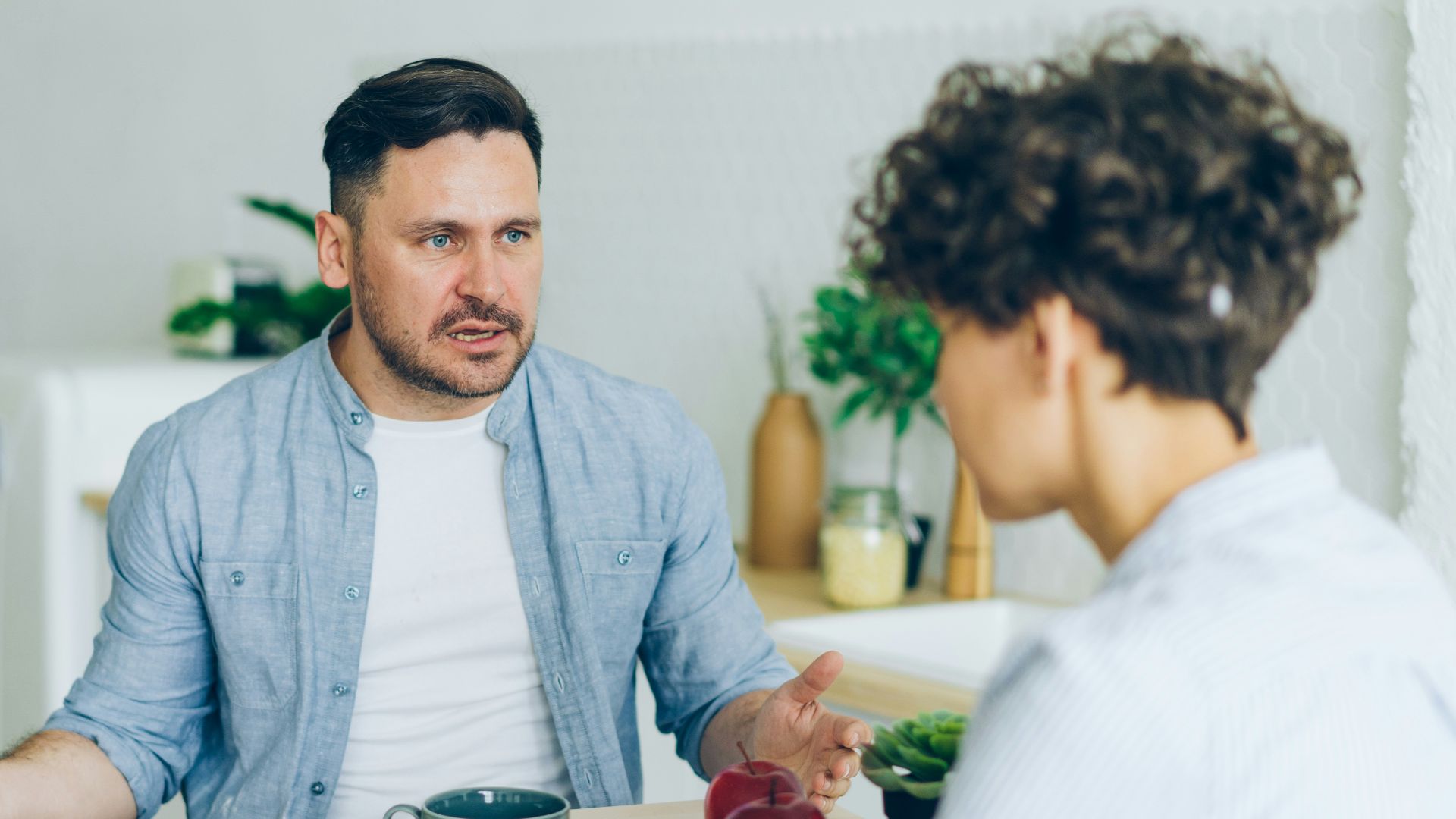 a man sitting at a table talking to a woman
