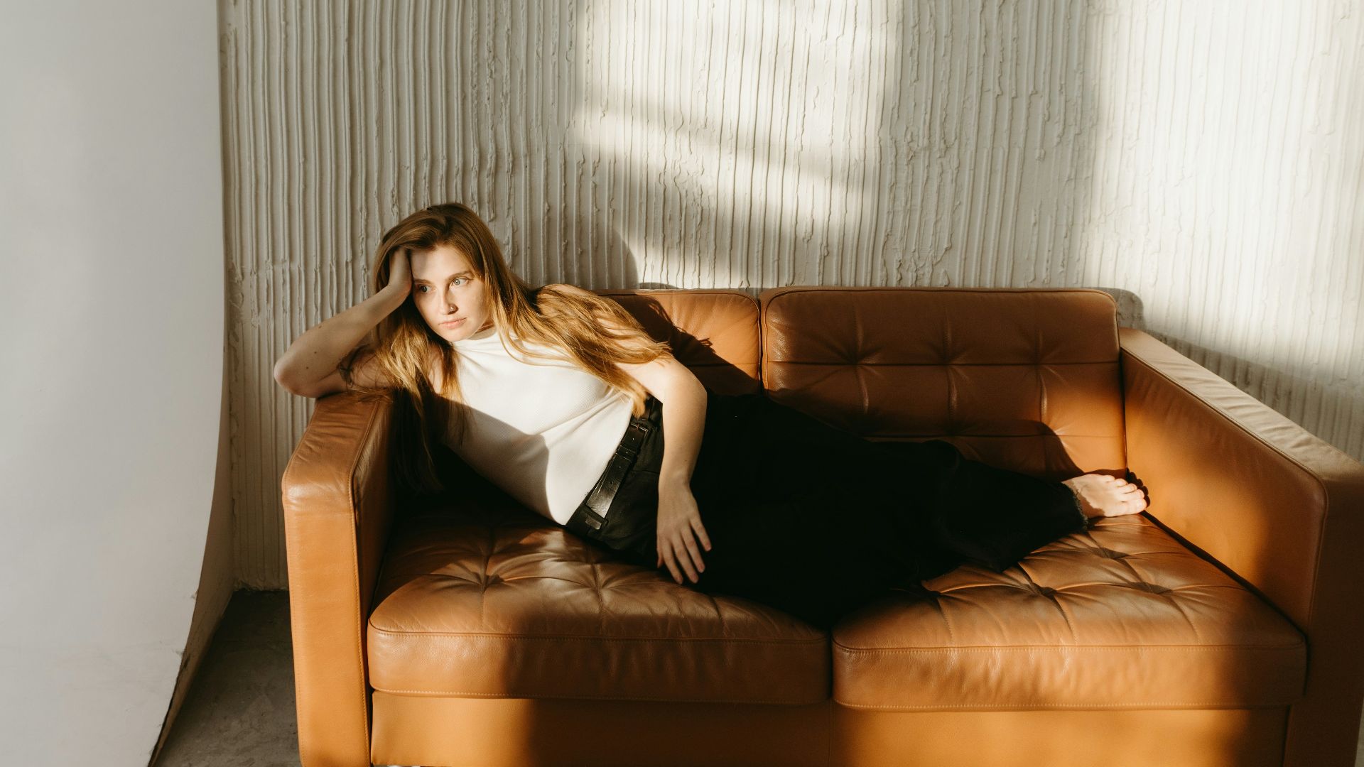 A woman relaxes on a brown couch.
