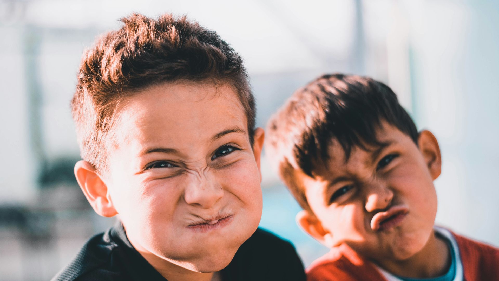 shallow focus photography of two boys doing wacky faces