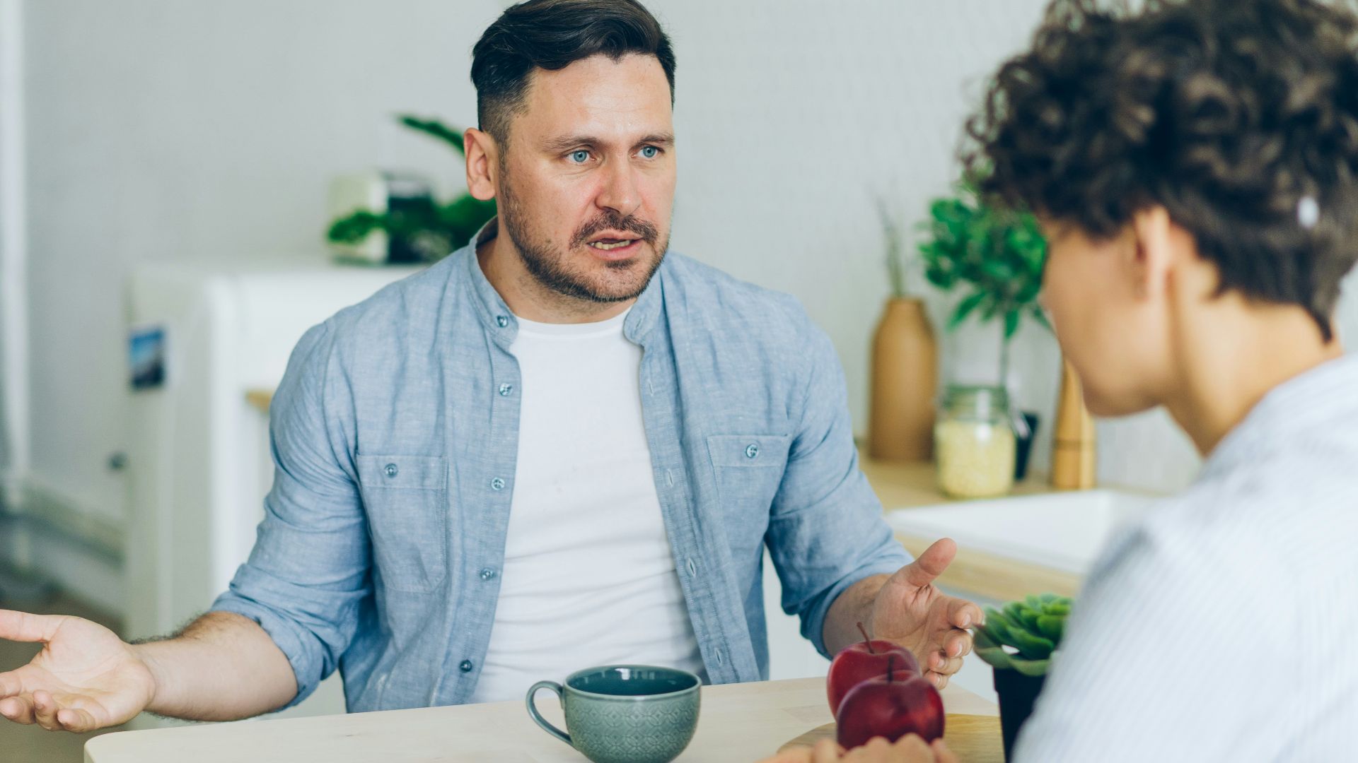 a man sitting at a table talking to a woman