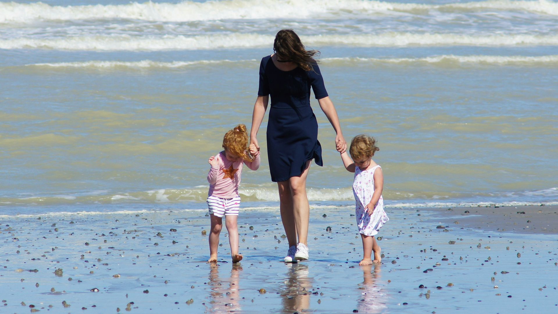 woman with 2 children walking on beach