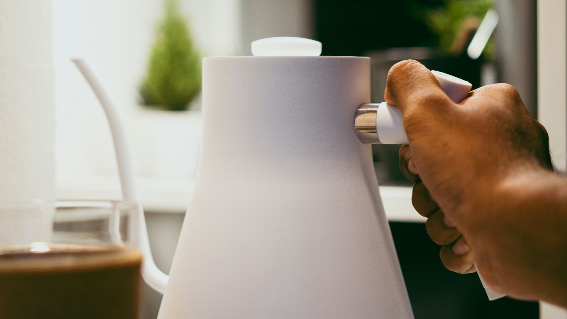 a person is holding a coffee pot on a table