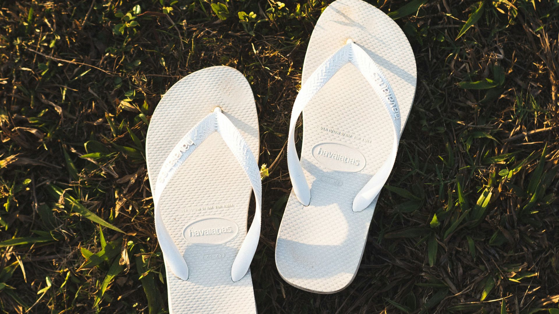 a pair of white slippers sitting on top of a lush green field