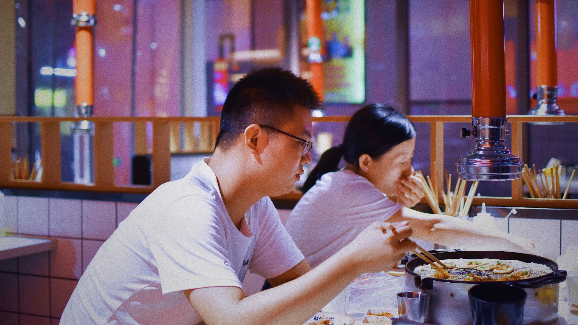 a man and a woman sitting at a table eating food