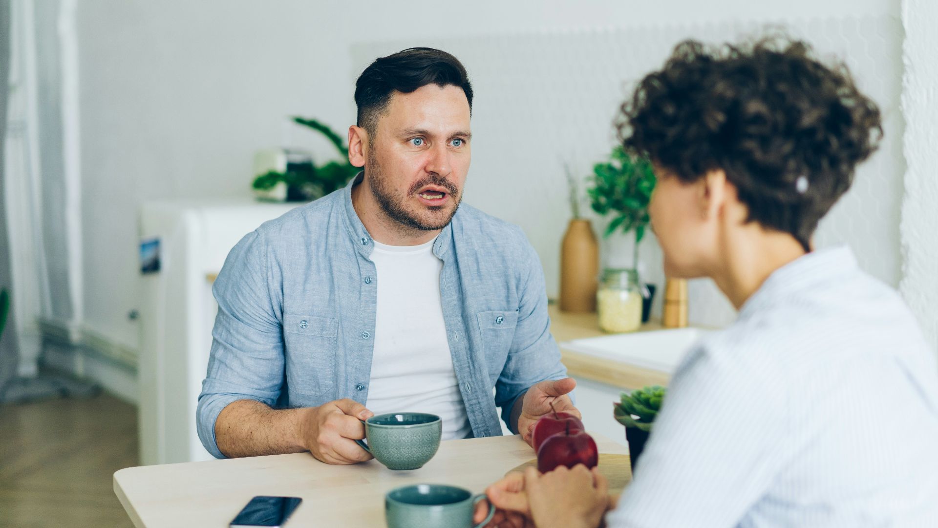 a man sitting at a table talking to a woman