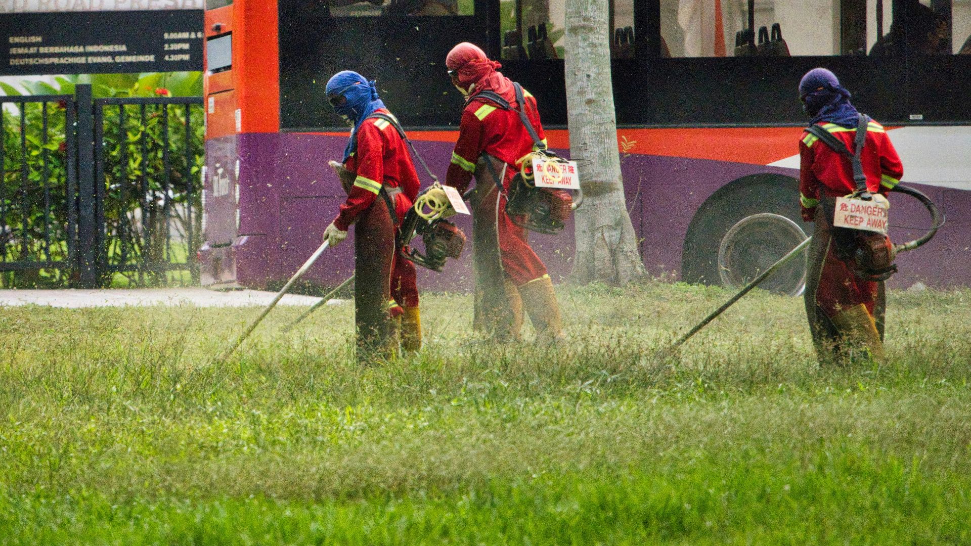 man in red jacket holding a stick near red bus during daytime