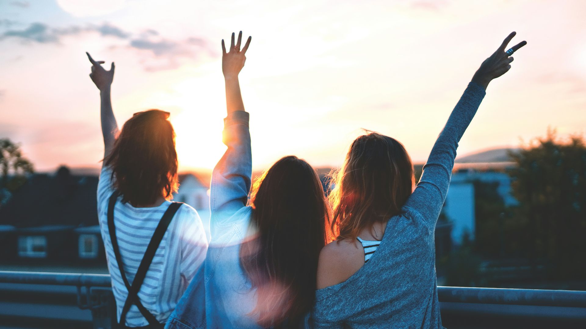 photo of three women lifting there hands \
