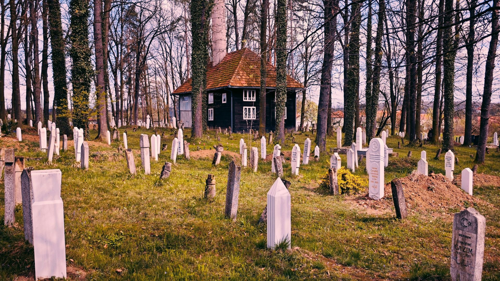 A cemetery with headstones and a small building.