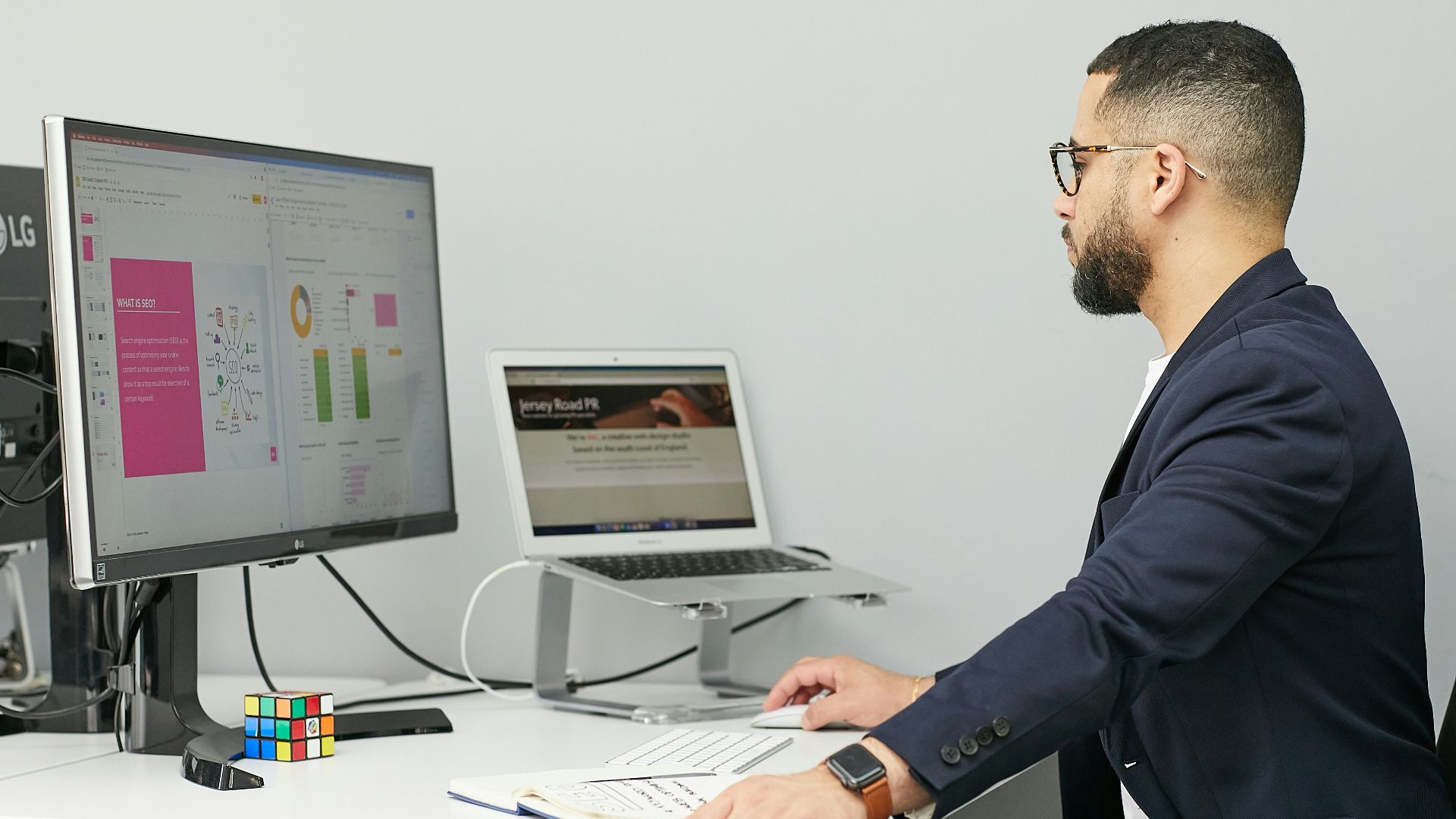 a man sitting at a desk with a laptop and a computer