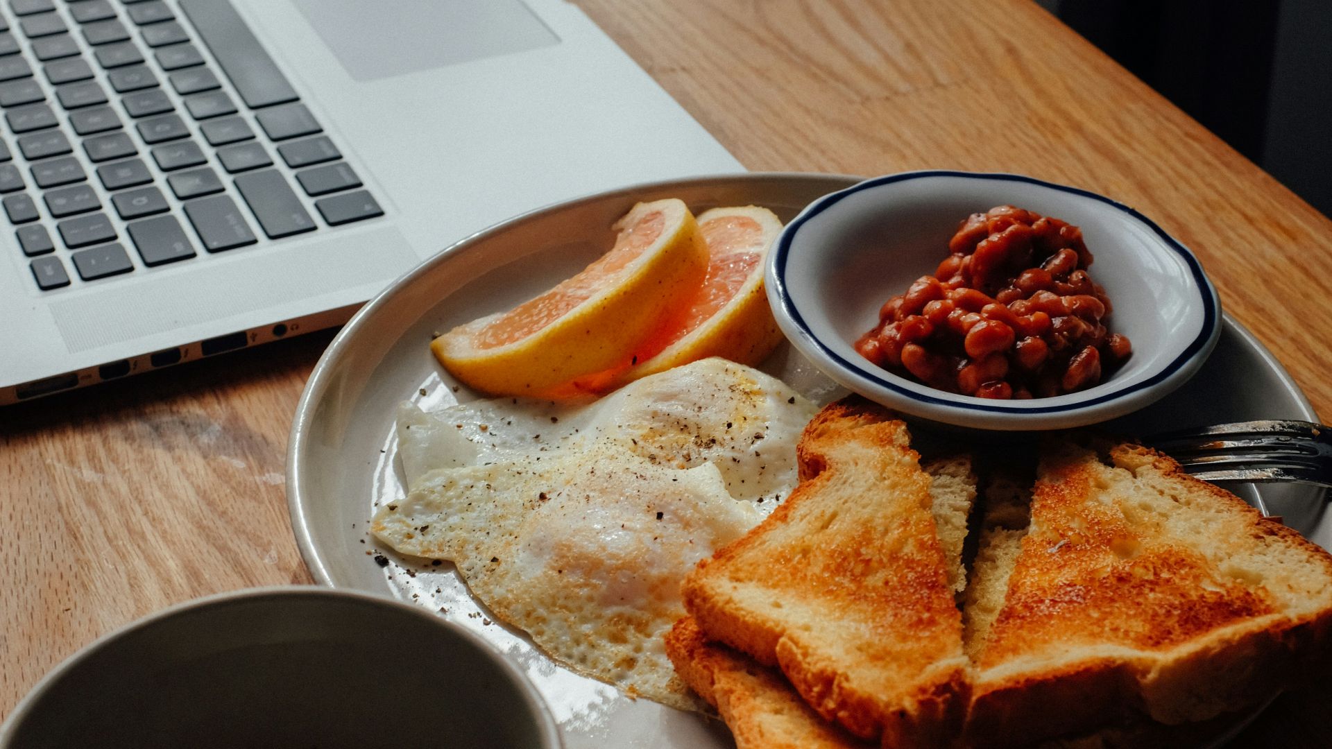 burger on brown wooden round plate beside black ceramic mug