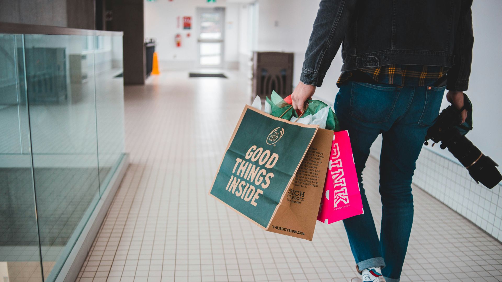 person walking while carrying a camera and paper bags