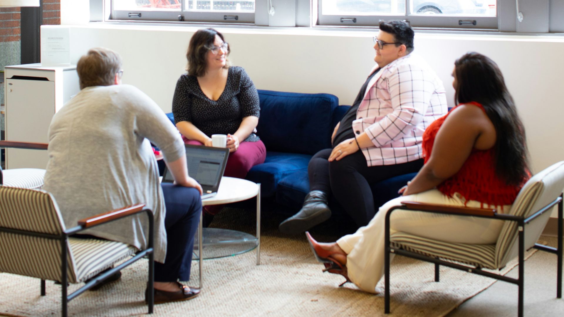 four persons sitting on chairs near window during daytime
