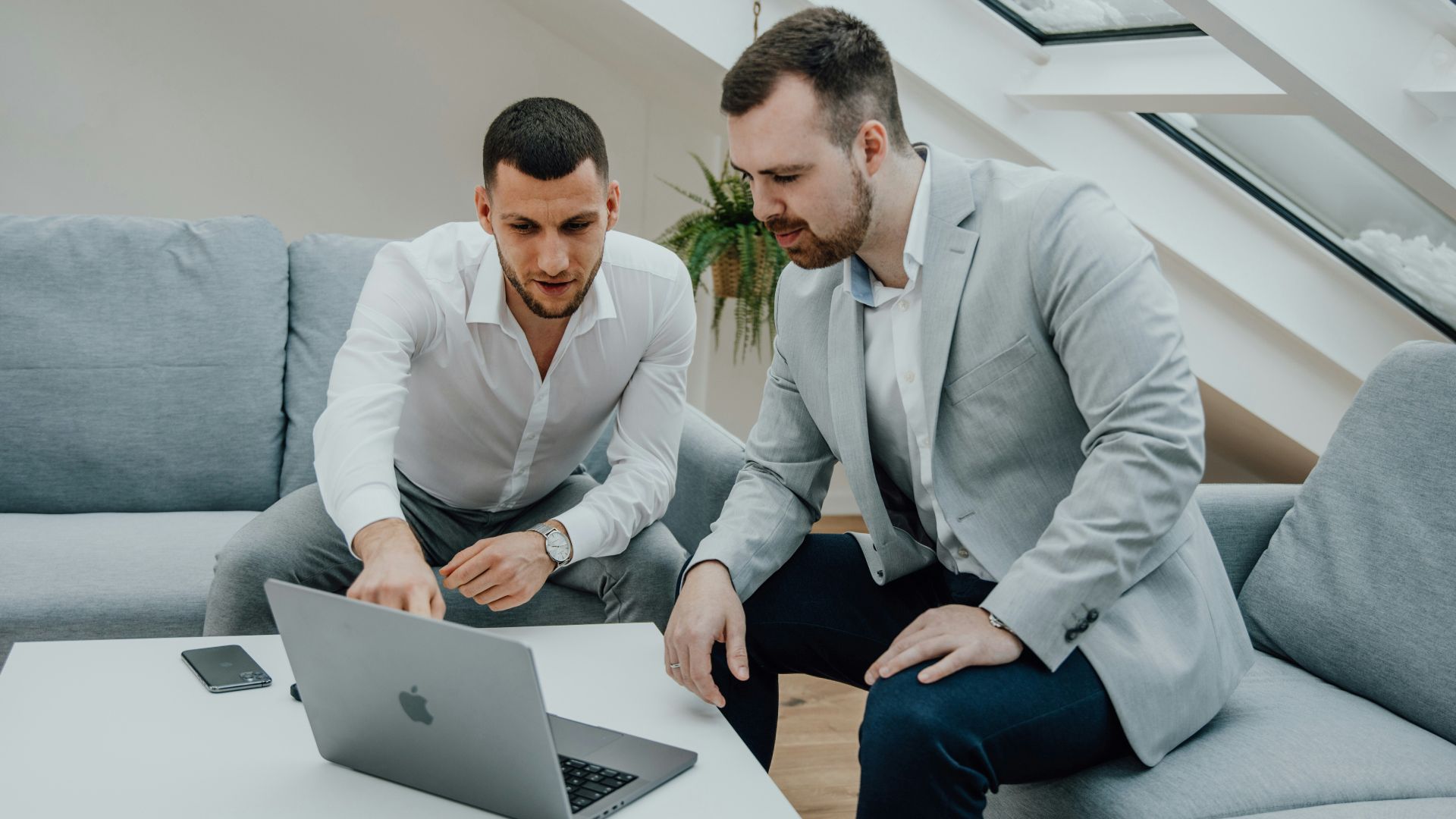 two men looking at a laptop on a table