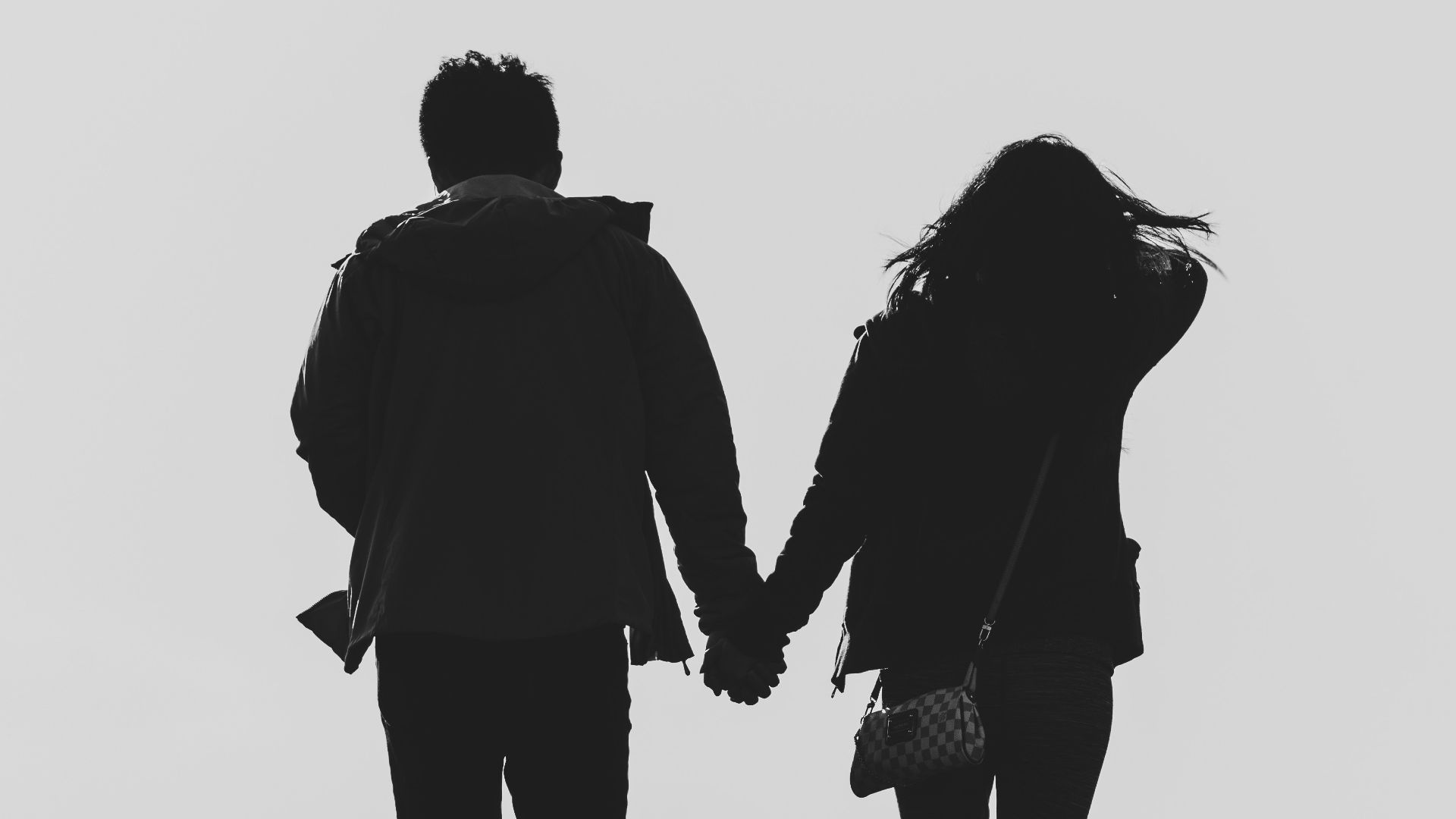 a man and a woman walking down a hill holding hands