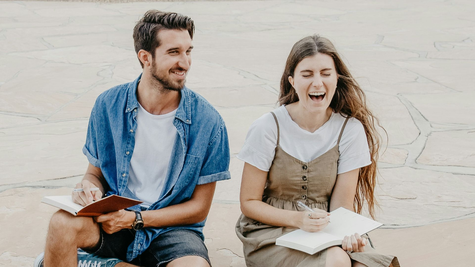 man and woman sitting side by side holding notebooks