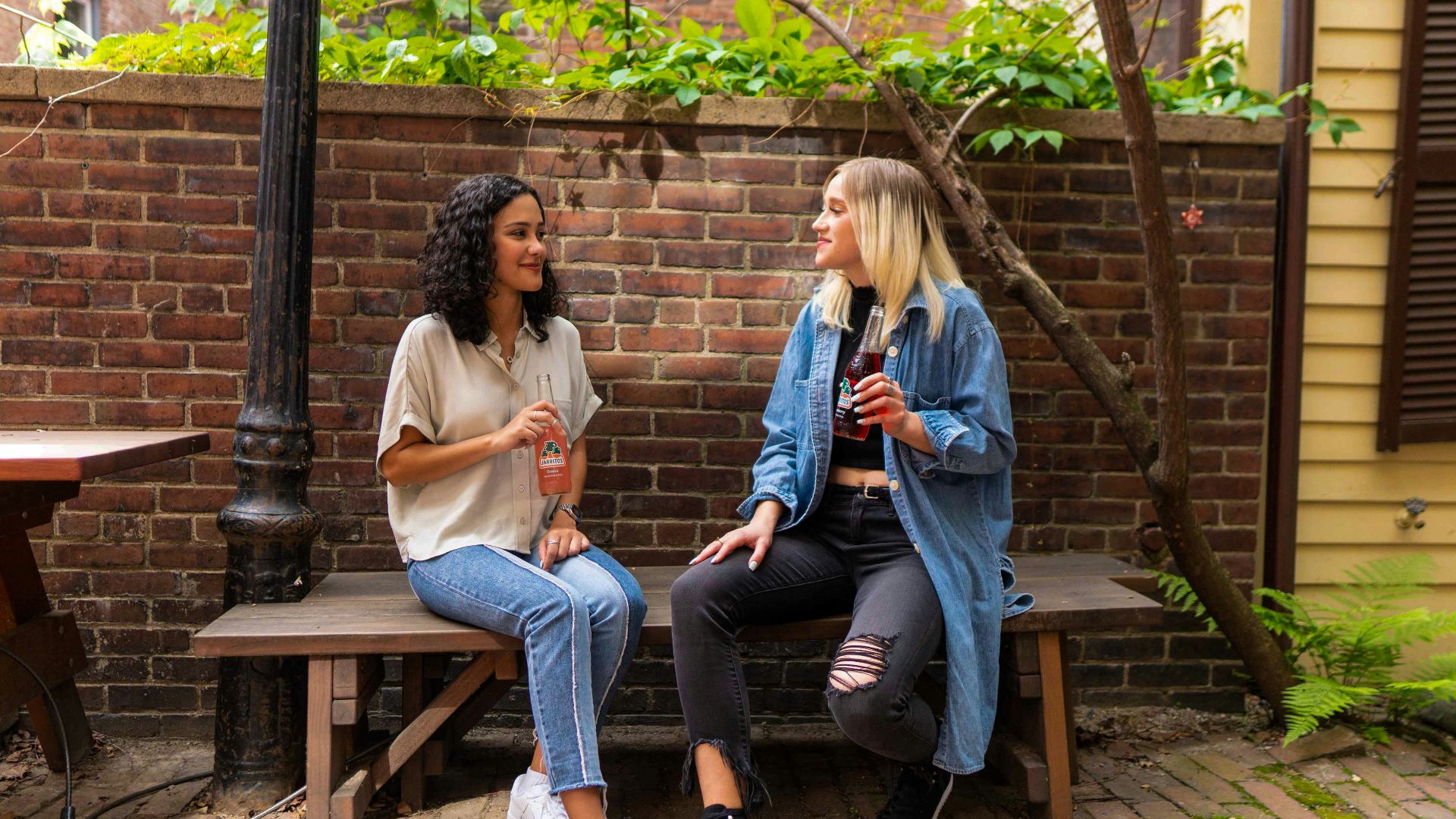 2 women sitting on brown wooden bench