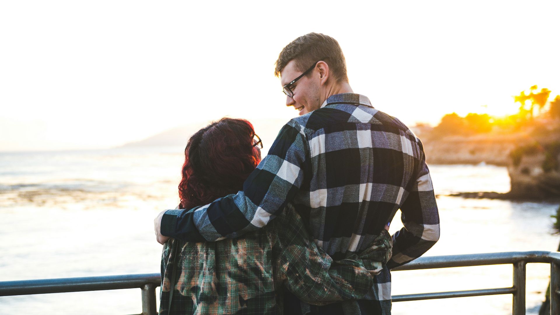 a man and woman kissing on a pier