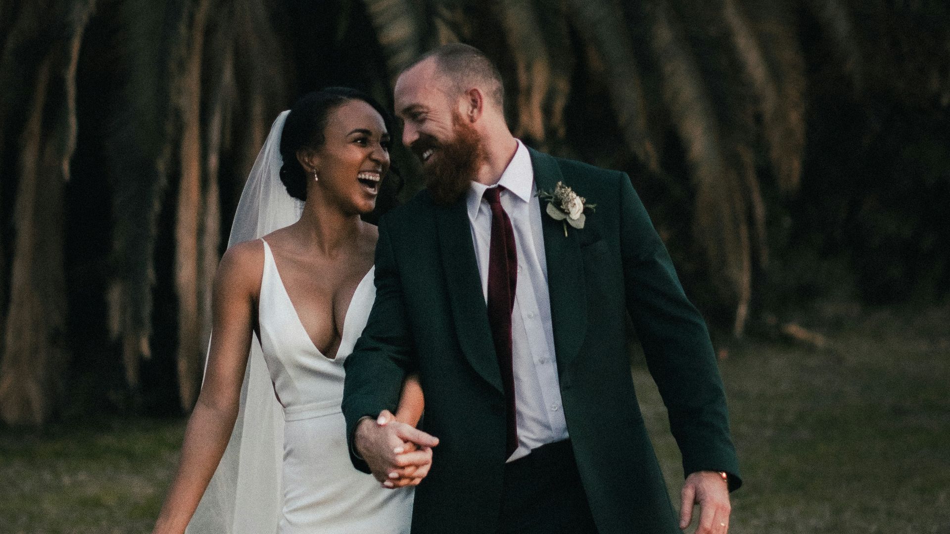 a newly married couple walking through a field
