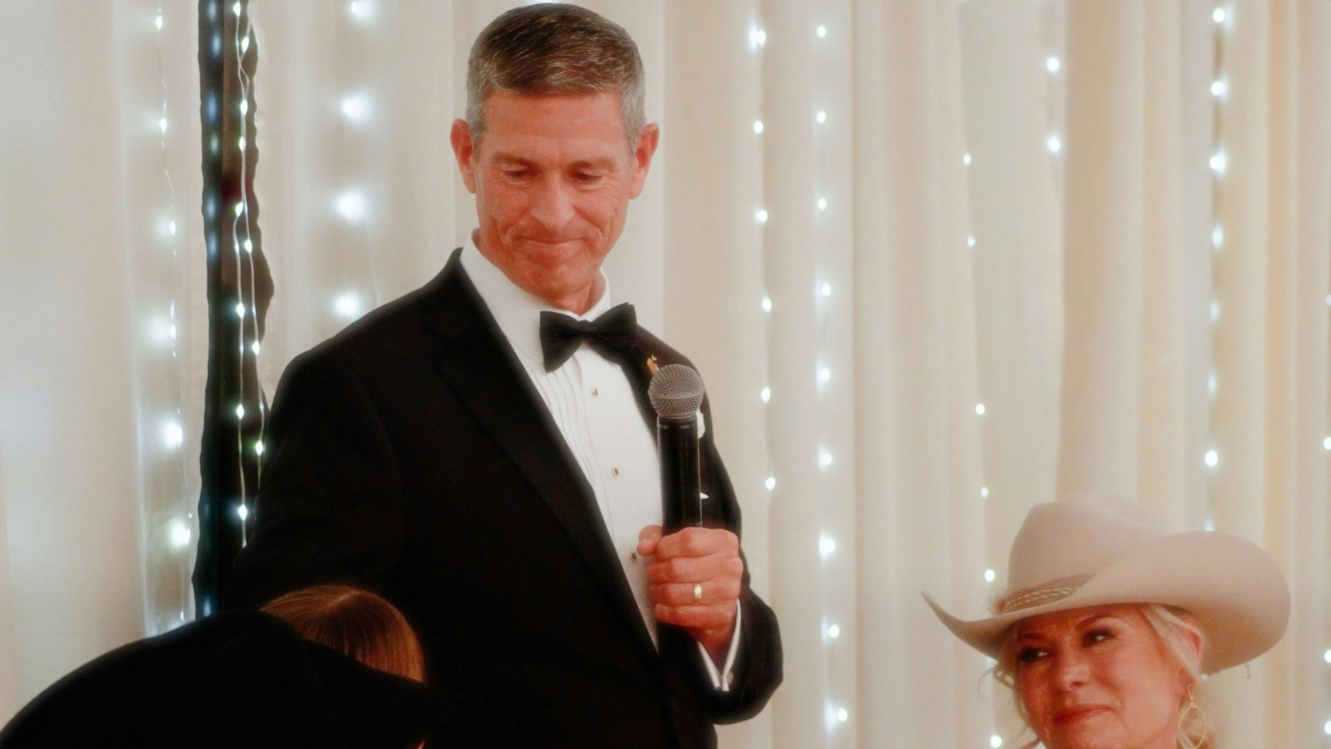 a man in a tuxedo standing next to a woman