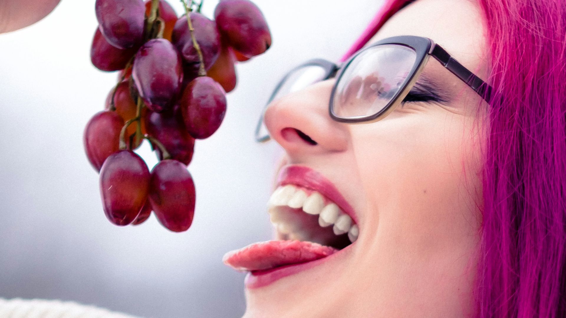 woman in gray sweater holding red round fruit
