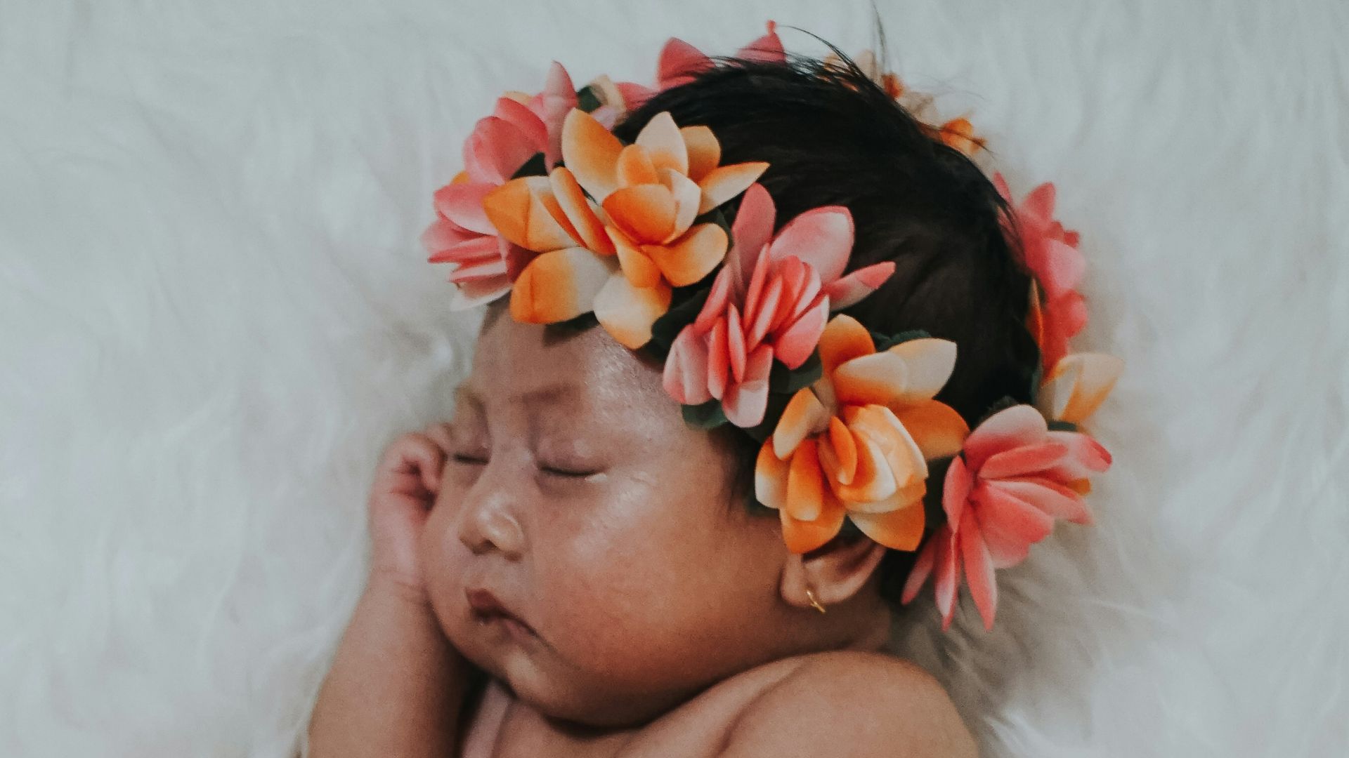 baby wears floral crown and covered with pink shawl