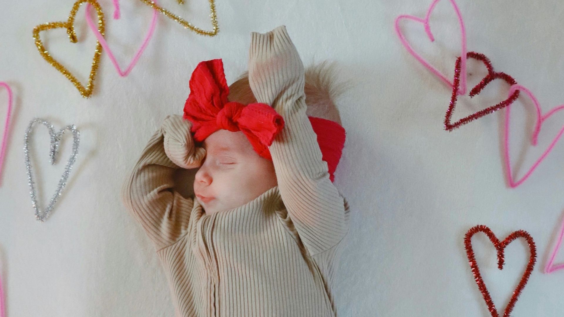 A baby is laying on a blanket with hearts around it