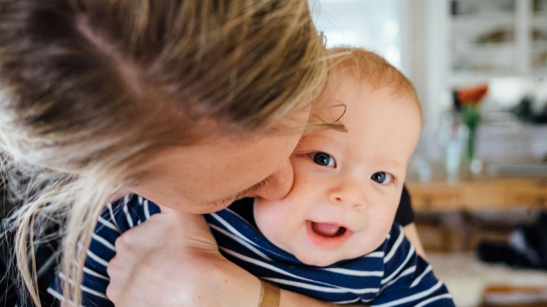 woman carrying baby in striped shirt