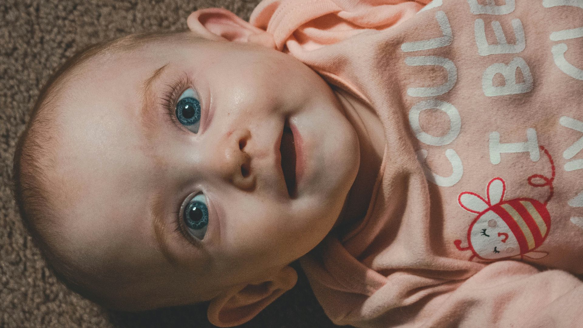 smiling child in long-sleeved top lying on brown canvas