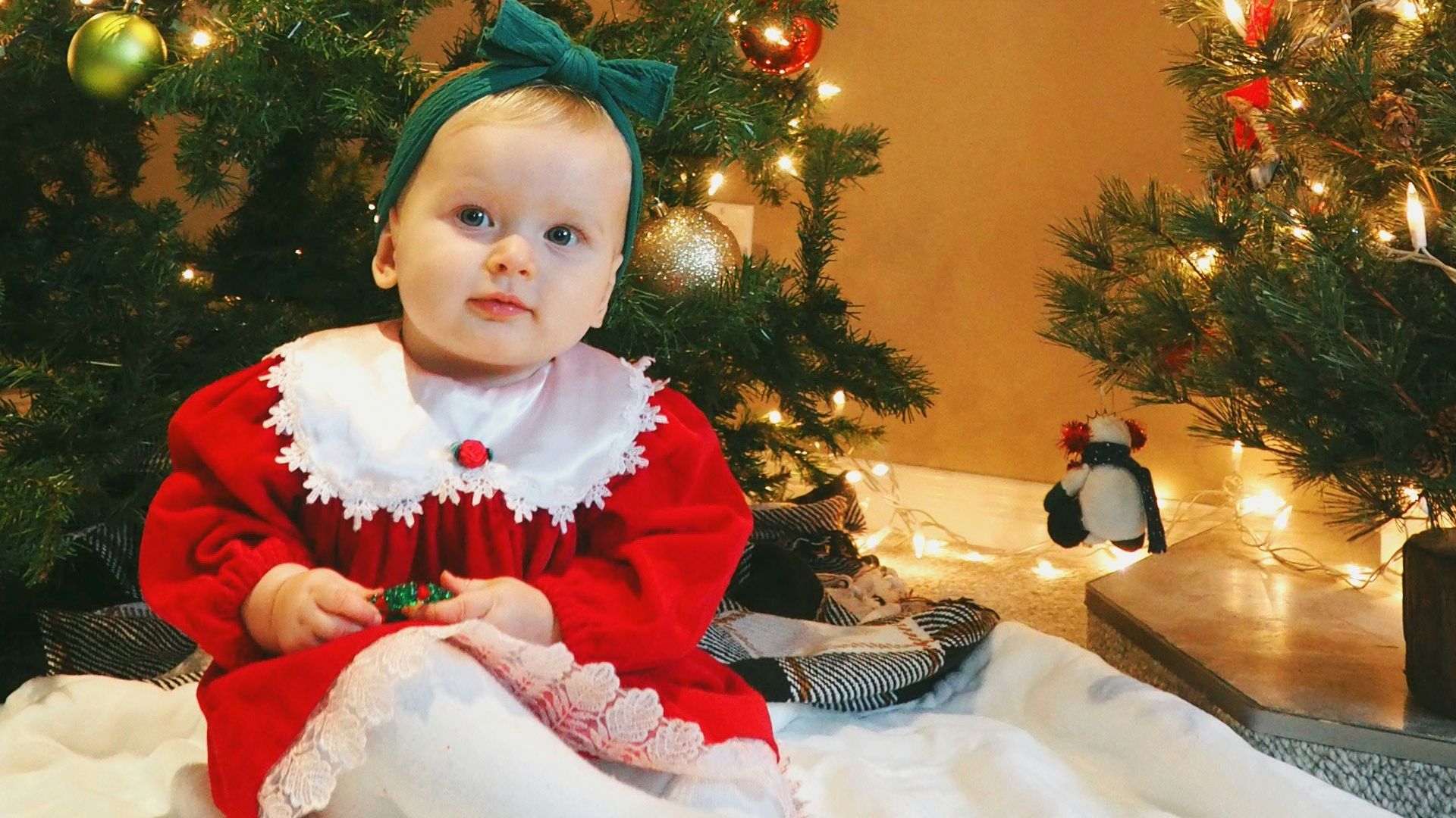 girl in red and white santa costume standing beside green christmas tree