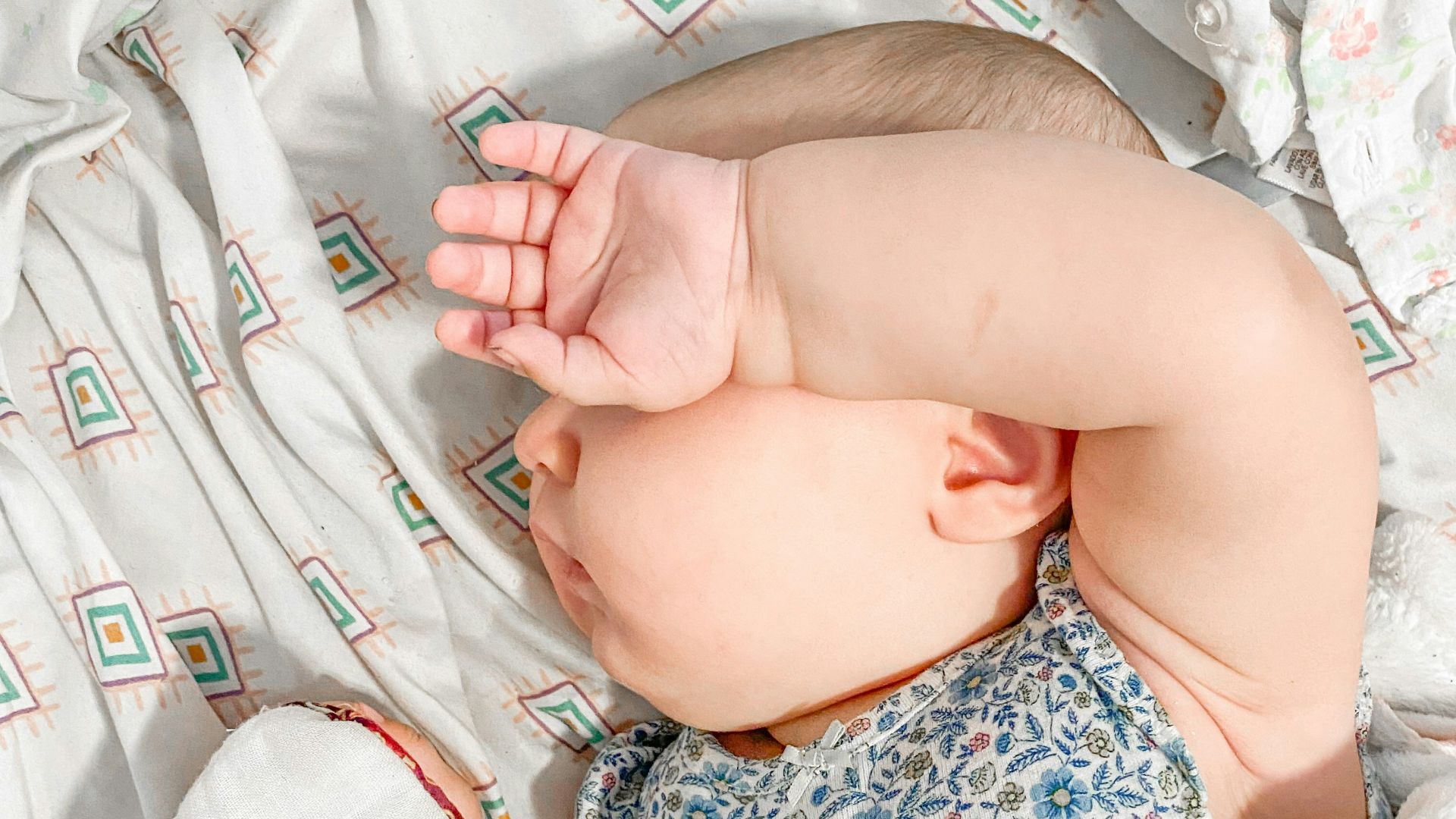 a baby laying on a bed with a white blanket