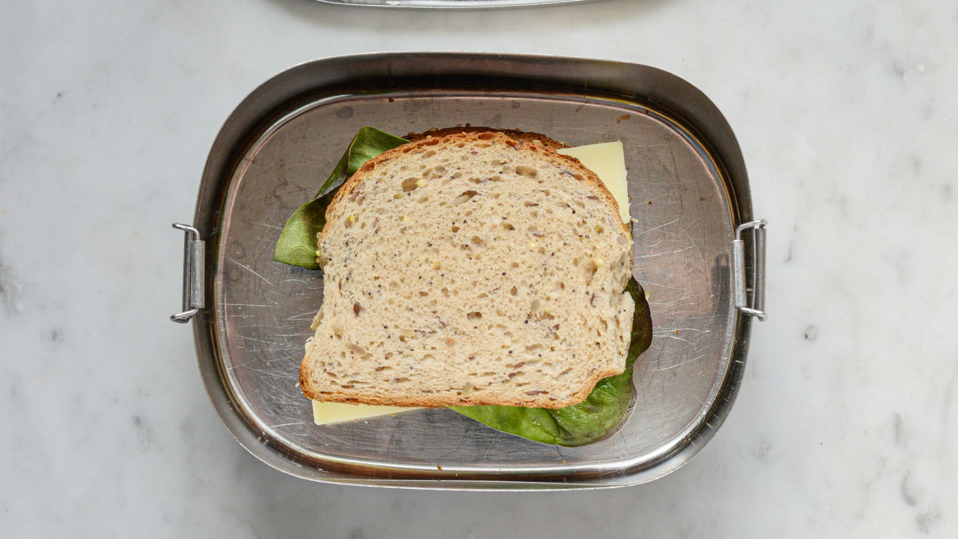 a sandwich in a metal container on a marble table