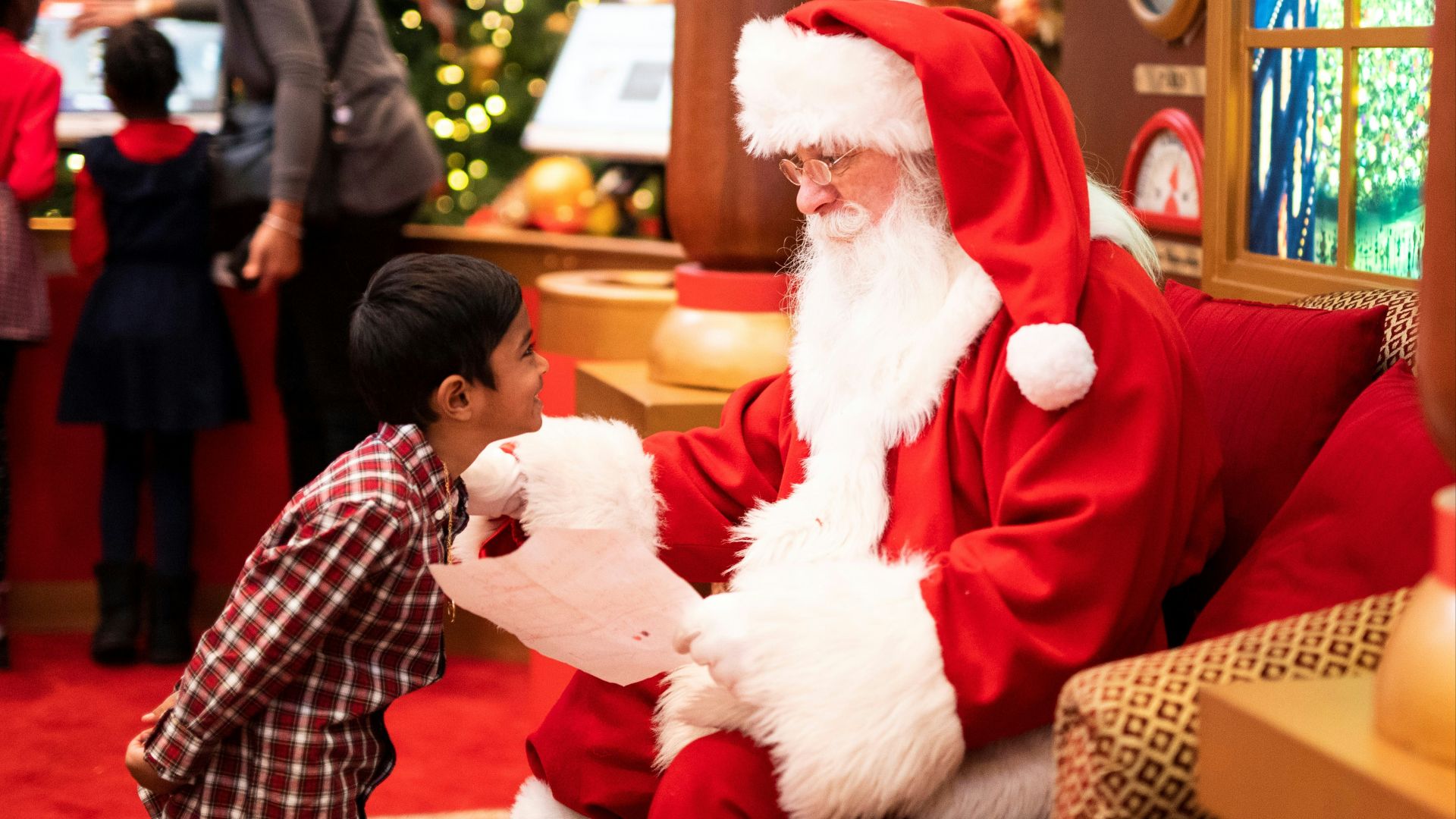 boy standing in front of man wearing Santa Claus costume