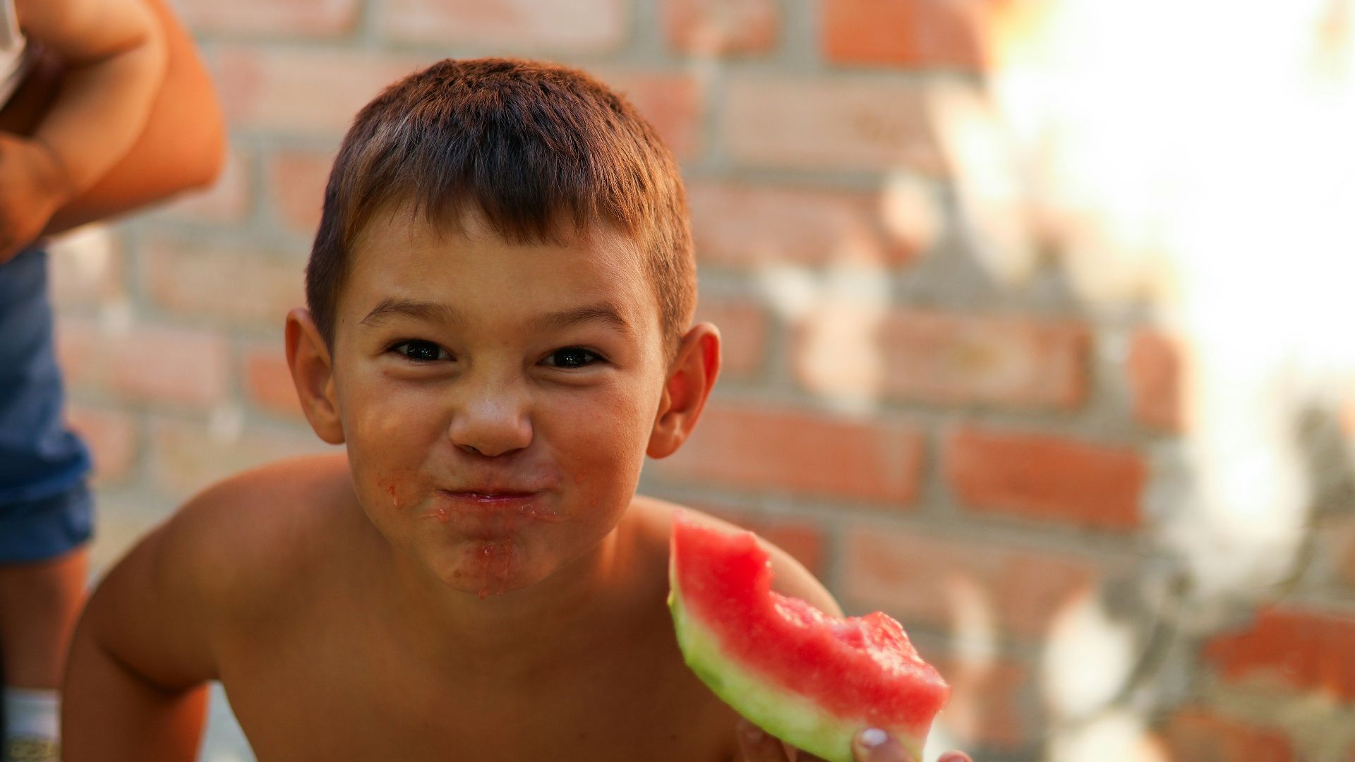 a young boy eating a piece of watermelon