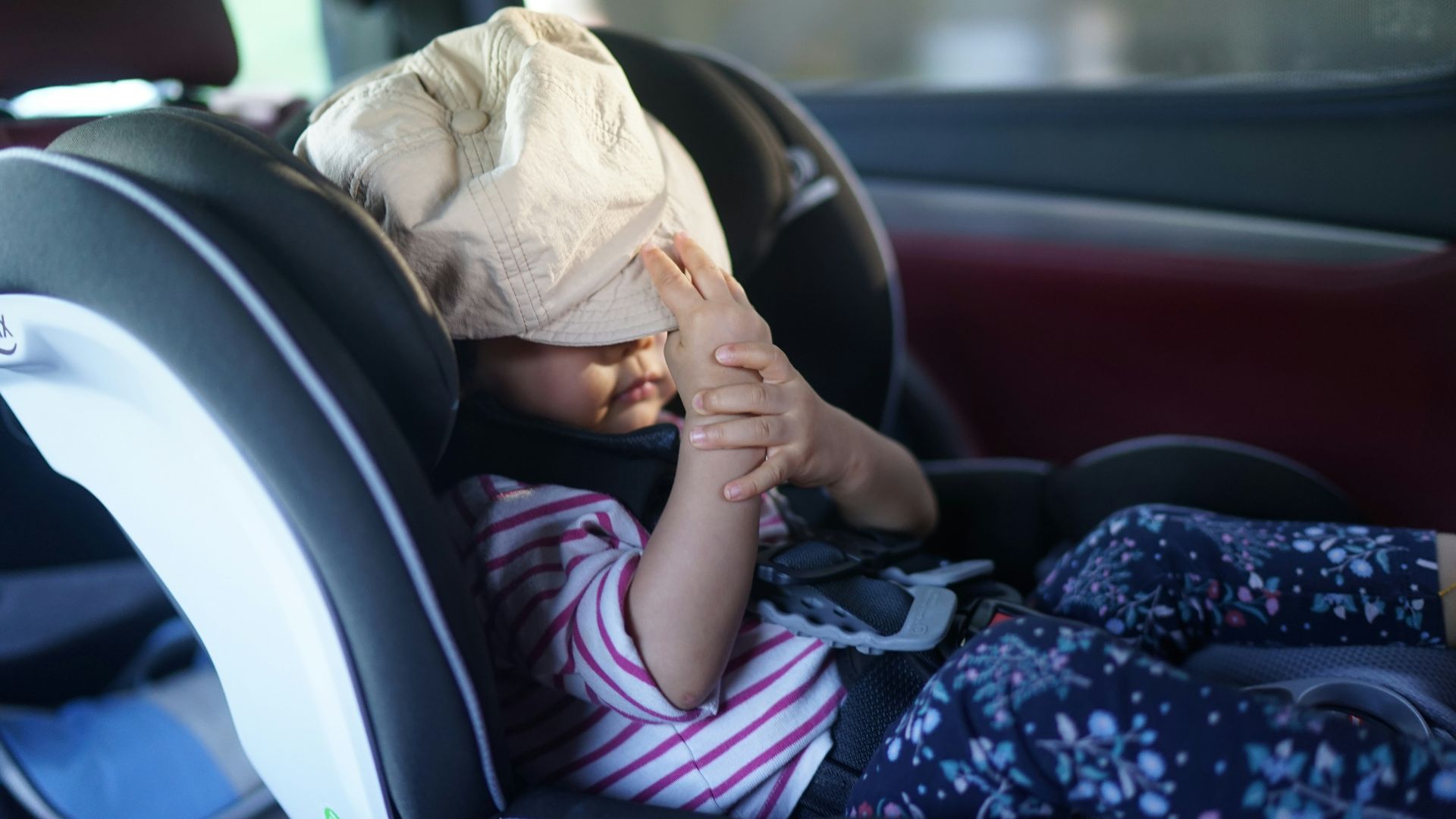 A child has a bag over their head in car.
