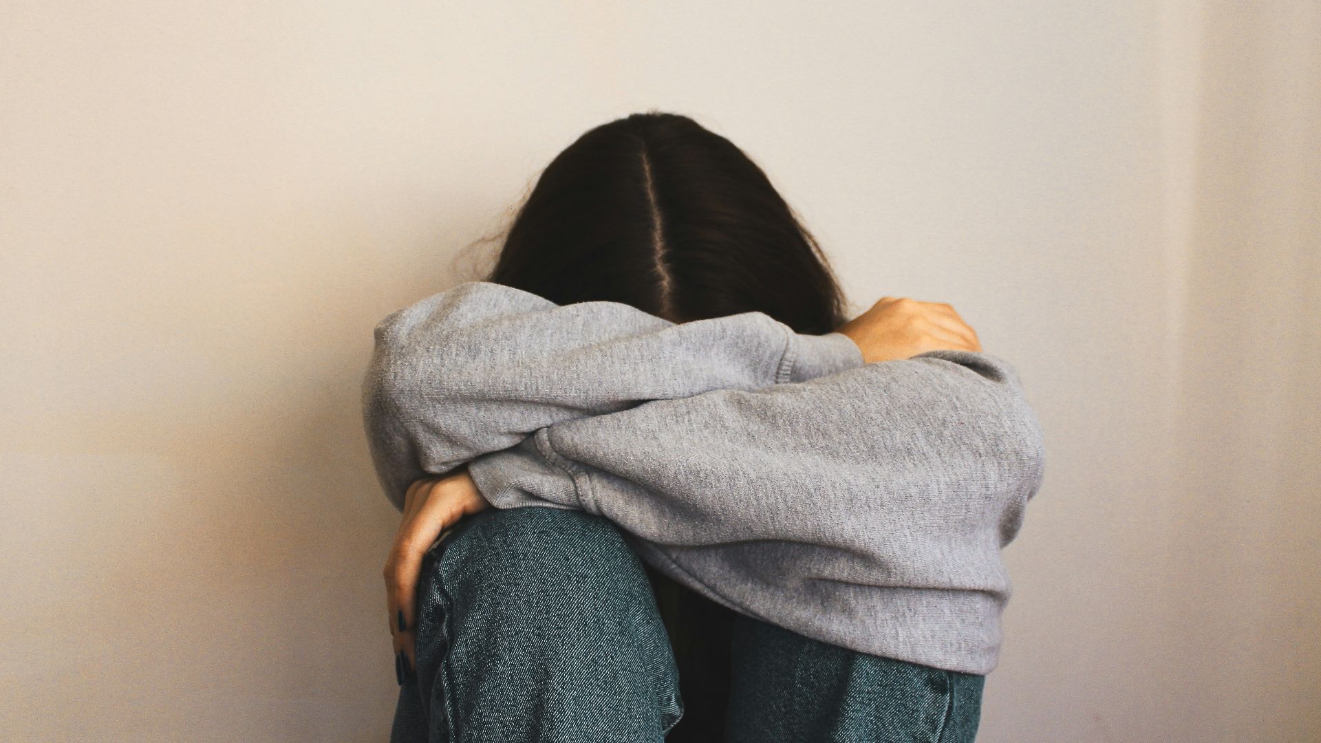 a woman sitting on the floor with her arms wrapped around her head