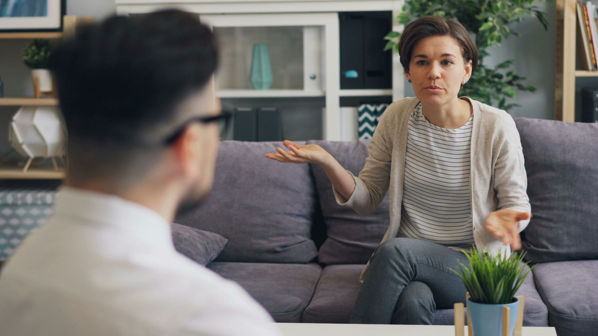 a woman sitting on a couch talking to a man