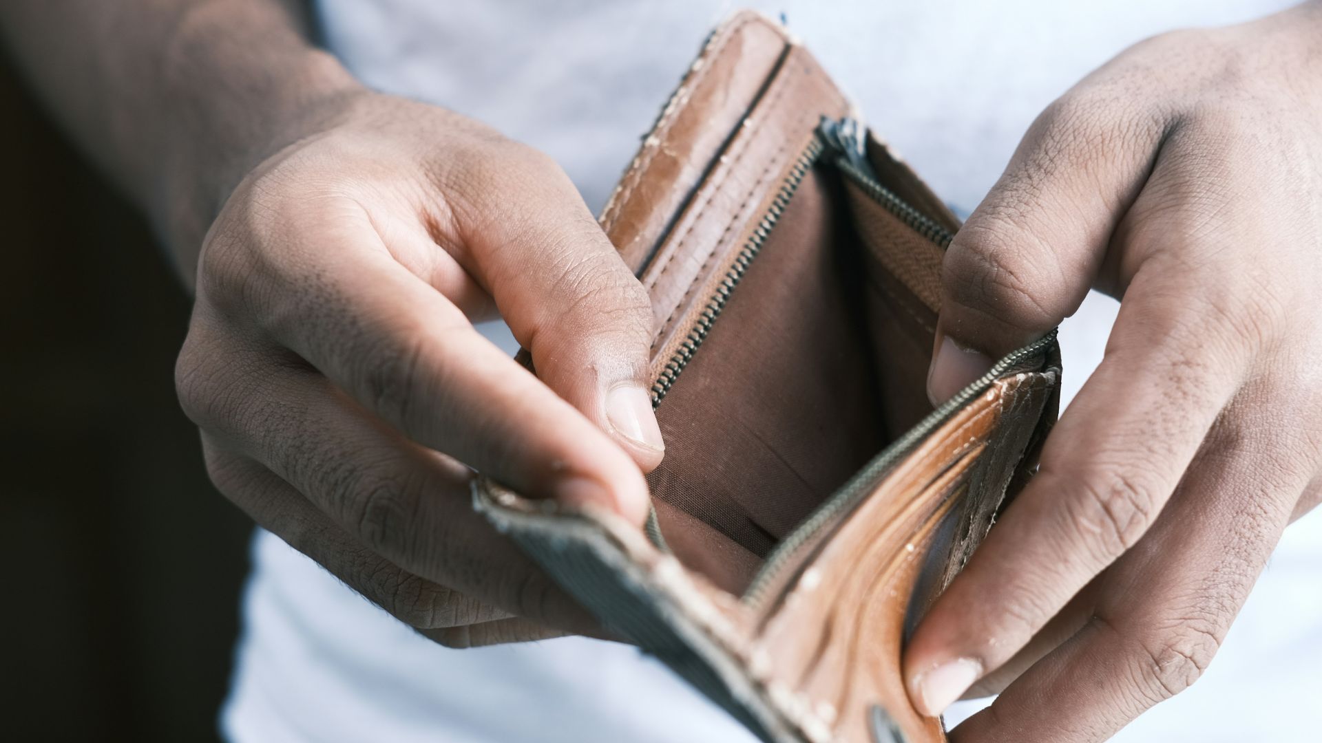person holding brown leather bifold wallet