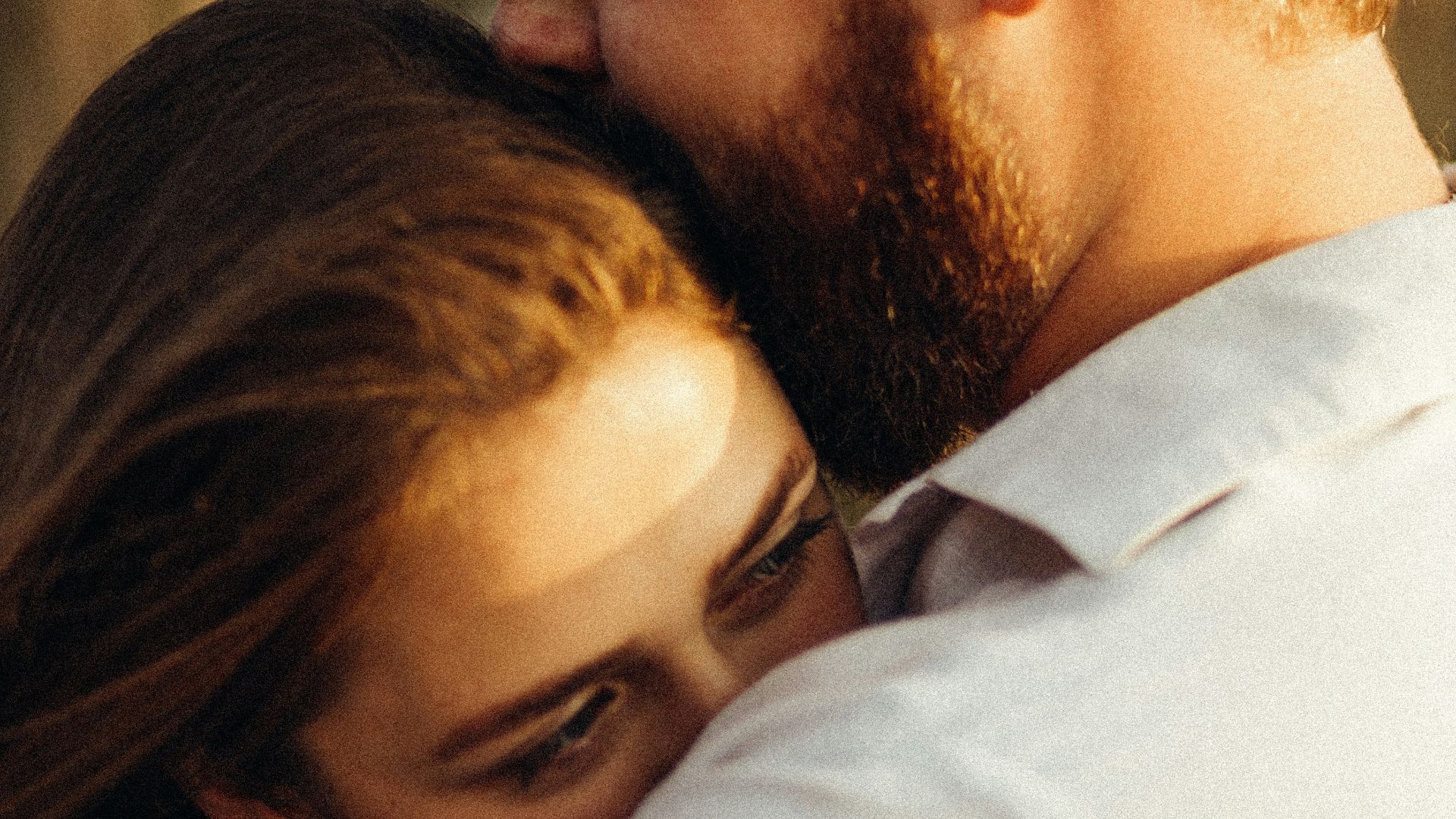 man in white dress shirt kissing woman in black hair