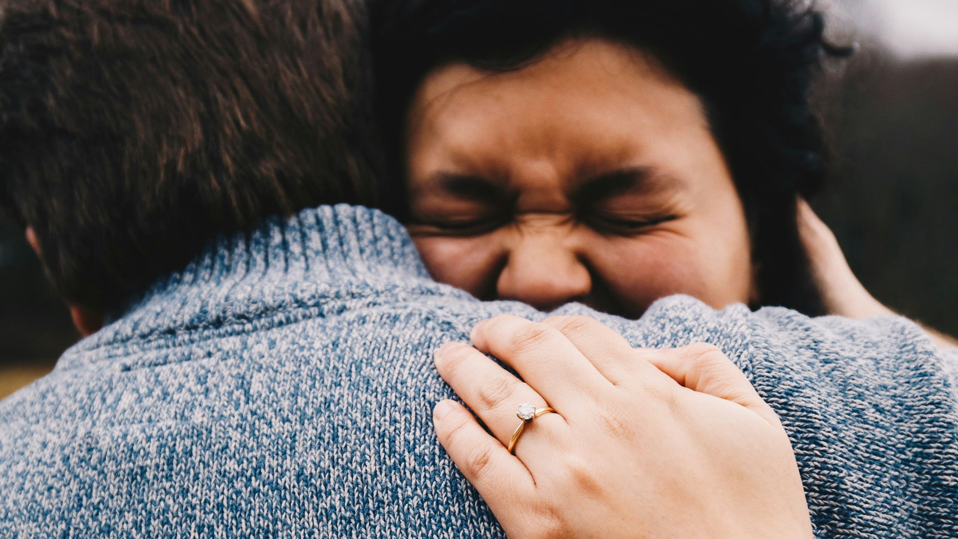 woman in gray knit sweater covering her face with her hand